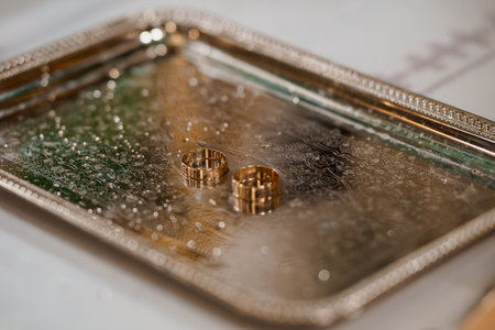 A close-up shot of two golden wedding bands presented on an ornate silver tray symbolizes a loving commitment, representing the union of two people during an exchange ceremonyの写真素材