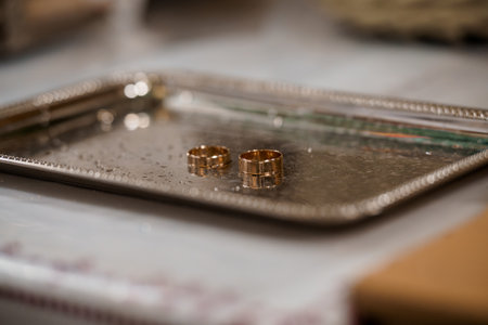 A close-up shot showcases two golden wedding rings gently placed on a vintage silver tray alongside blurred marriage certificates, evoking romance and commitmentの写真素材