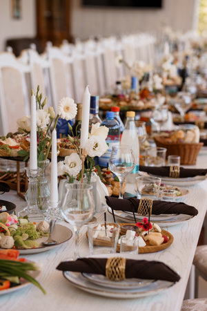 Beautifully arranged wedding reception table showcases a lavish feast with white linens, delicate floral arrangements, and glassware, suggesting a joyful celebrationの写真素材
