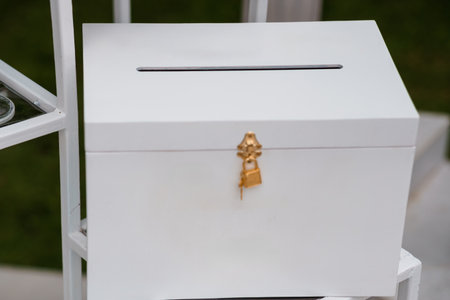 A pristine white card box adorned with a decorative golden lock sits prominently at a wedding...