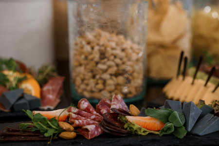 A sophisticated charcuterie board showcasing assorted cured meats, nuts in a glass jar, cheeses, and fresh garnishes. ideal for food blogs, restaurants, or festive eventsの写真素材