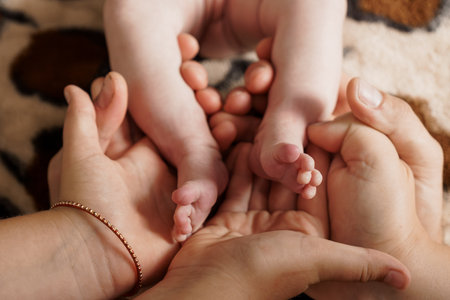 A heartwarming close-up shot depicts multiple hands gently cradling the tiny feet of a newborn baby, symbolizing parental love, family bonding, and tender careの写真素材