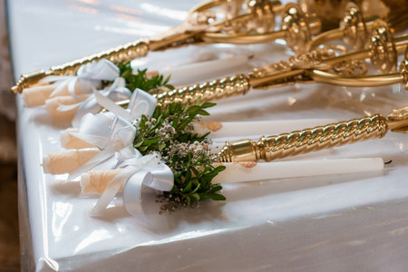 Beautifully decorated wedding unity candles feature ivory ribbons, delicate white flowers, and lush greenery laid on a pristine table setting, symbolizing love and commitmentの写真素材