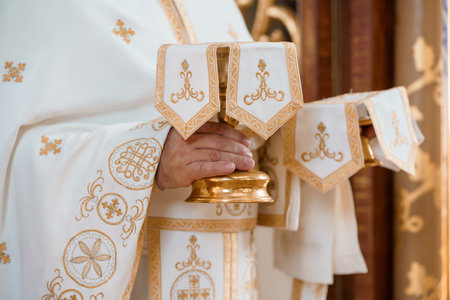 Close-up shot of an Eastern Orthodox priest presenting a golden chalice during a sacred liturgical celebration, showcasing ornate vestments and rich religious symbolismの写真素材