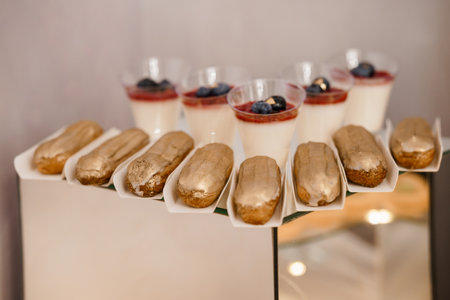 A close-up shot showcases a beautifully arranged dessert display featuring golden-glazed eclairs...