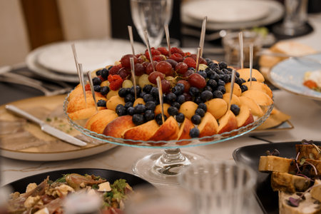 A beautifully arranged fruit platter showcasing grapes, blueberries, peaches, and melon sits on a...