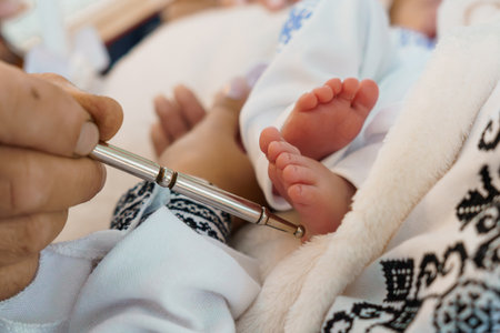 Close-up shot of a healthcare provider administering a heel prick blood test to a newborn baby,...