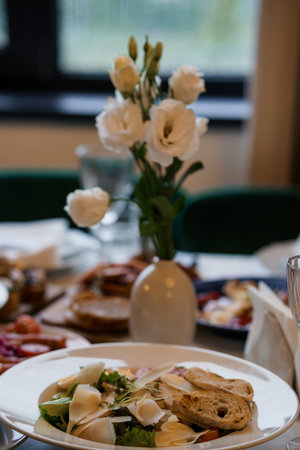 Elegant White Lisianthus Bouquet with Gourmet Salad, Soft Indoor Lighting, Green and Cream Decor, Lifestyle Photography.の写真素材