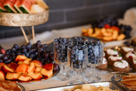 Fresh Fruit Platter with Blueberries in Glasses, Elegant Party Food Display, Dark Background, Silver Tray, Appetizers, and Festive Moodの写真素材