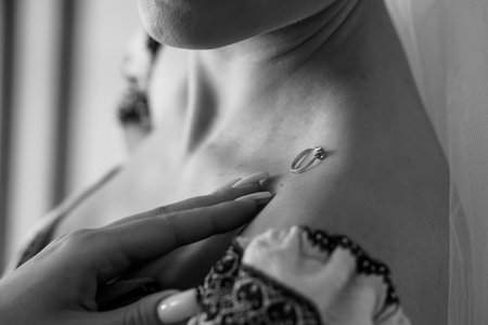 A close-up black and white photograph capturing a bride tenderly holding her wedding ring close to her chest, adorned in delicate lace lingerie. Conveys romance and anticipation.の写真素材