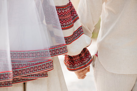 A close-up depicts shots of a Ukrainian wedding couple holding hands, showing intricately...
