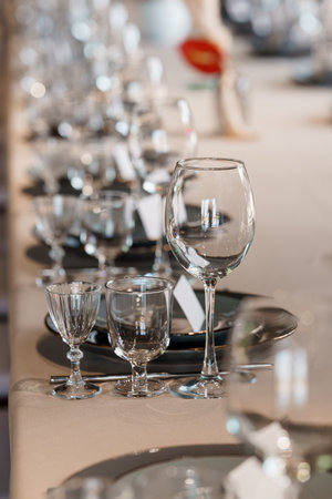 A beautifully arranged wedding or formal event table features sparkling crystal glasses, black plates, and soft beige linens creating an atmosphere of refined luxury and celebrationの写真素材