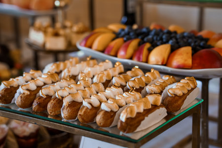 A close-up showcases a lavish dessert buffet featuring rows of cream puffs with caramelized tops...