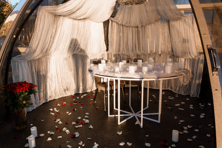 An intimate dinner setting inside a clear glass igloo, featuring a circular table adorned with white...