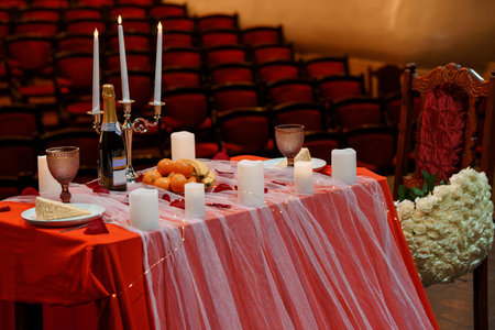 Romantic Red Table Setting with Candles, Champagne, and Flowers in an Elegant Auditorium Venueの写真素材