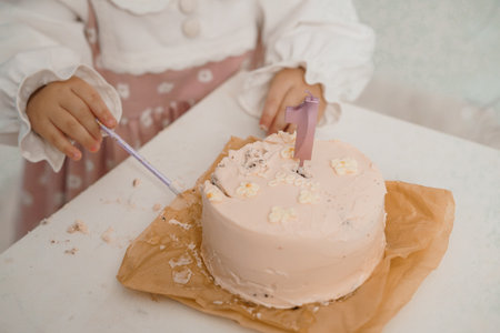 Adorable One-Year-Old Child Celebrating First Birthday with Pink Cake and Number 1 Candle in Soft Pastel Settingの写真素材