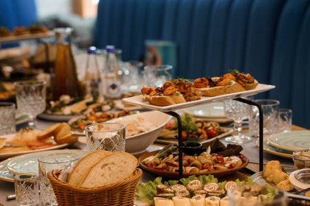 A lavish buffet table features an array of appetizers, artisan bread, salads, and drinks arranged in...