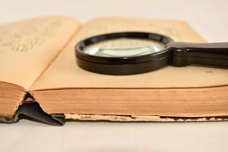An old book with a magnifying glass on a white backgroundの写真素材