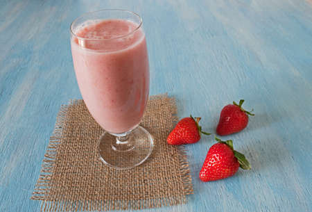 Strawberry healthy milkshake with fresh berries on blue wooden blackground. Strawberry Helthy Smoothie.の写真素材
