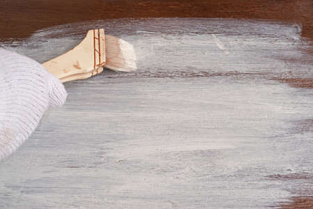 The hand holding the brush. Wooden board paint in white color.の写真素材