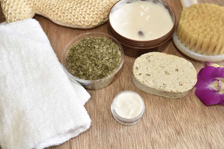 Spa and wellness setting with natural soap and orchid, sea salt, massage oils and soft towel.