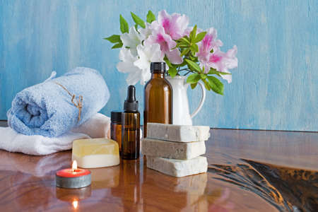 Spa and wellness setting with natural soap and flowers, candles, massage oils and soft blue towel.の写真素材