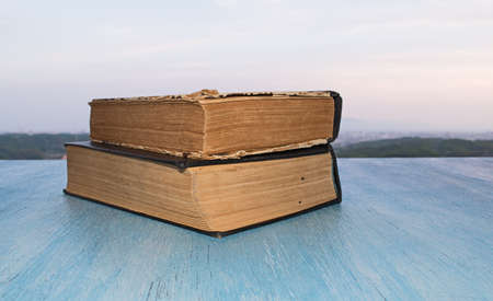 Stack of old books on the wooden blue table the background of the beautiful skyの写真素材