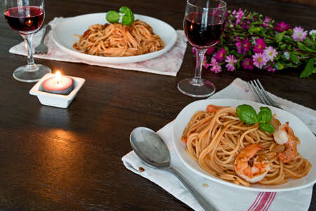 Spaghetti in tomato sauce. Romantic dinner with wine and flowers, asters conceptの写真素材
