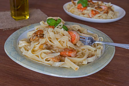 Fettuccini pasta in cream sauce with shrimp and mussels. decorated basil leavesの写真素材