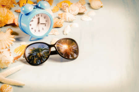 background with alarm clocks, sunglasses and seashells, summer holiday and vacation time concept.の写真素材