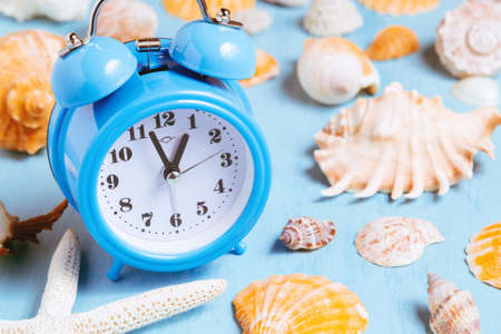 Blue sea background with alarm clocks and seashells, summer holiday and vacation time concept