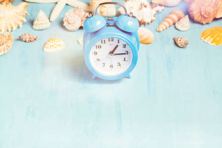 Blue sea background with alarm clocks and seashells, summer holiday and vacation time concept