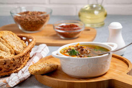 Lentil soup with chicken in a white bowl on a wooden board on a gray table and ingredientsの写真素材