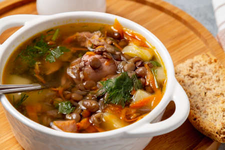 Lentil soup with chicken in a white bowl on a wooden boardの写真素材