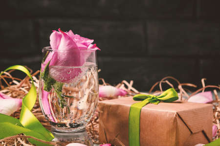 Pink rose in a glass with water and decorations on the tableの写真素材