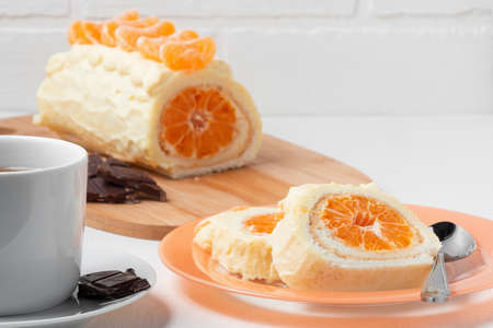Sweet roll with whipped cream and tangerine filling and a cup of teaの写真素材