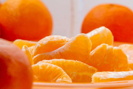 Several whole and peeled ripe tangerines on a orange plateの写真素材