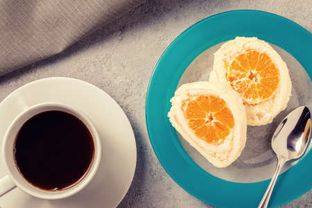 Sweet roll with whipped cream and tangerine filling and a cup of coffeeの写真素材