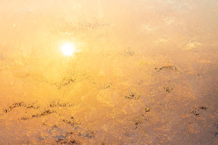 Nature background with ice pattern and sunlight on winter window