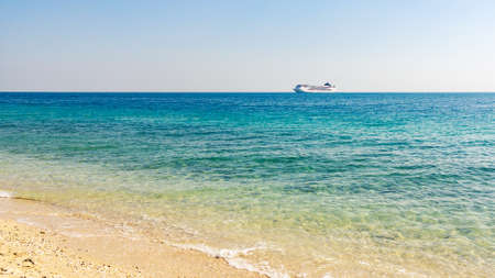 Turquoise sea with light ripples on the water and a large cruise liner on the horizonの写真素材