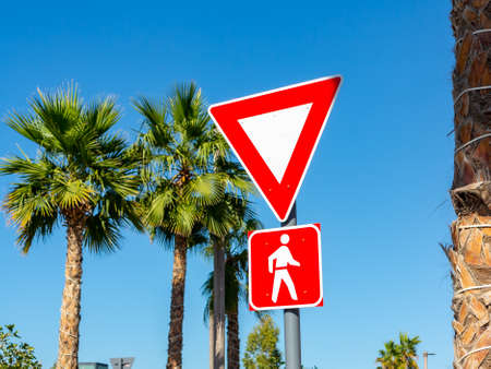 Dubai, United Arab Emirates - December 12, 2018: Yield To Pedestrians Sign in red frames against the blue sky and palmのeditorial素材