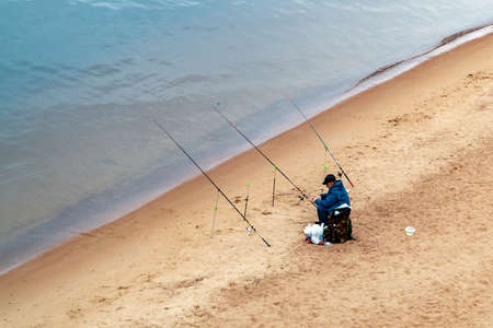 St. Petersburg, Russia - July 10, 2018: fisherman are fishing on the sandy shores of the Gulf of Finland under the bridgeのeditorial素材