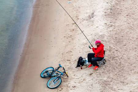 St. Petersburg, Russia - July 10, 2018: fisherman are fishing on the sandy shores of the Gulf of Finland under the bridgeのeditorial素材