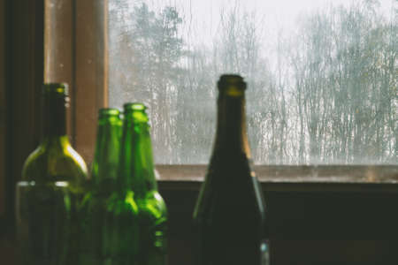 Several empty bottles of alcohol near the dirty window. Selective focus. Alcoholism, drunkenness,...