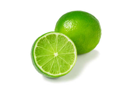Fresh ripe limes, one whole and one half isolated on white background with shadow - image