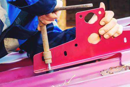 Male hands twist the screw into the roof of the metal tiles. Installing snow guard