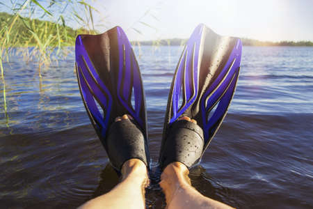 Womens legs in flippers by the lake on a hot summer dayの写真素材