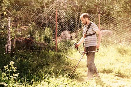 A man mows the grass in his garden with a trimmerの写真素材