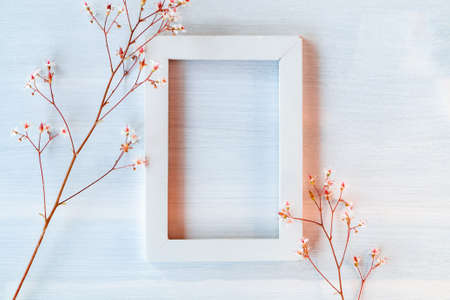 White wooden frame on a white textured background with small flowers - a template for a greeting card or invitationの写真素材