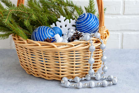 Christmas composition - wicker basket with decorations and fir branches on a light background